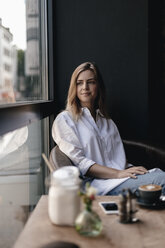 Young woman sitting in cafe, looking out of window - GUSF00196