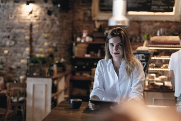 Smiling blond woman sitting in cafe, using tablet - GUSF00202