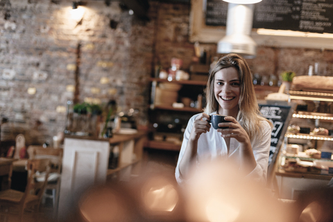 Junge Frau in einem Café sitzend, lachend, Kaffee trinkend, lizenzfreies Stockfoto