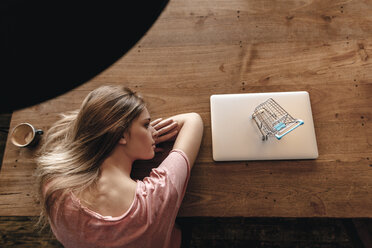 Junge Frau betrachtet den Einkaufswagen auf dem Laptop, Online-Shopping - GUSF00208