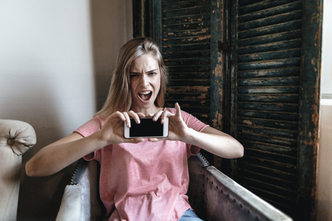 Schreiende junge Frau macht Smartphone-Selfie, lizenzfreies Stockfoto