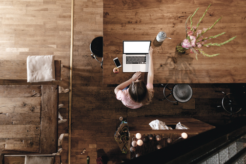 Blonde Frau sitzt in einem Café und arbeitet an ihrem Laptop, lizenzfreies Stockfoto