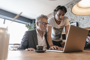 Vater und Sohn arbeiten zusammen in einem Café und benutzen einen Laptop - GUSF00231