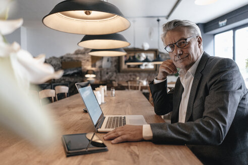 Älterer Geschäftsmann sitzt im Café und arbeitet am Laptop - GUSF00236