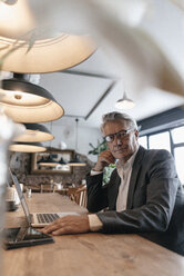 Senior businessman sitting in cafe working on laptop - GUSF00237