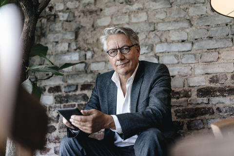 Geschäftsmann sitzt im Café und benutzt sein Smartphone, lizenzfreies Stockfoto