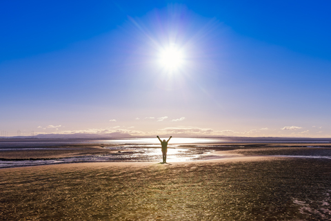 Großbritannien, Schottland, Solway Firth, Silhouette einer Touristin, erhobene Arme, lizenzfreies Stockfoto