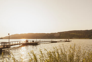 Germany, Bavaria, Allgaeu, Grosser Alpsee, people on jetty at sunset - GWF05317