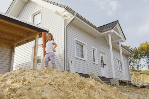 Happy blond girl standing on heap of sand near construction site of a detached one-family house stock photo