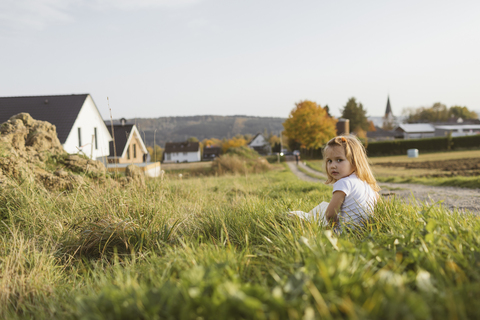 Portrait of blond little girl sitting on a meadow with a book stock photo