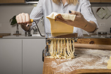 Woman preparing homemade pasta, using pasta maker - MAUF01260