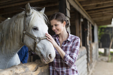Lächelnde Frau, die sich auf einem Bauernhof um ein Pferd kümmert - SHKF00802