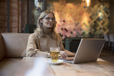 Porträt einer Geschäftsfrau, die in einem Restaurant am Laptop arbeitet - SUF00340