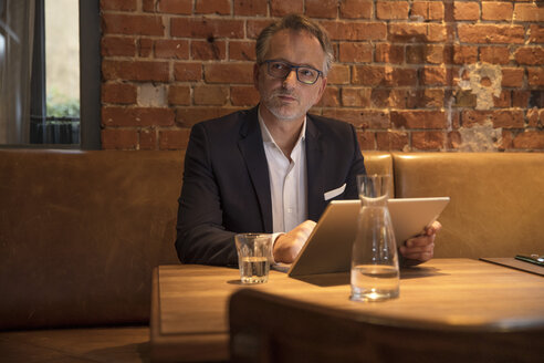 Porträt eines nachdenklichen Geschäftsmannes mit Tablet in einem Restaurant - SUF00359