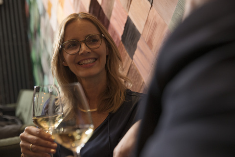 Porträt einer lachenden Frau, die in einer Bar Wein trinkt, lizenzfreies Stockfoto