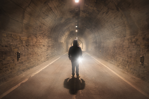 Spain, Huesca, young man exploring a dark tunnel stock photo