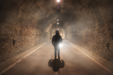 Spain, Huesca, young man exploring a dark tunnel - DHCF00164
