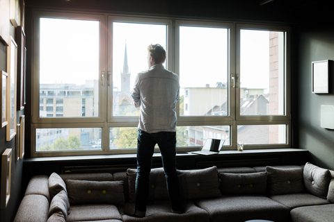 Geschäftsmann im Aufenthaltsraum eines Büros mit Blick aus dem Fenster, lizenzfreies Stockfoto