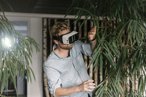 Man wearing VR glasses surrounded by plants stock photo