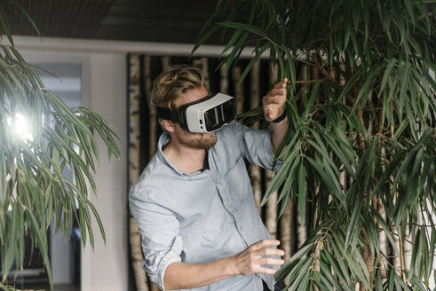 Man wearing VR glasses surrounded by plants - JOSF02019