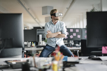 Businessman wearing VR glasses in office - JOSF02029