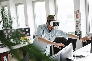 Businessman wearing VR glasses in office - JOSF02031