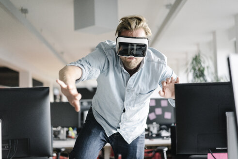 Businessman wearing VR glasses in office - JOSF02032