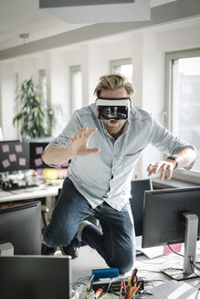 Businessman wearing VR glasses in office pretending to be a lion - JOSF02034