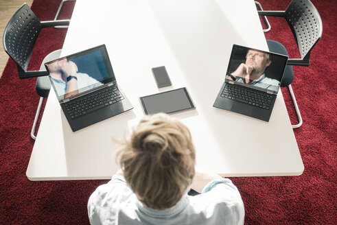 Geschäftsmann mit zwei Laptops, die Bilder von ihm selbst zeigen - JOSF02043