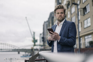 Businessman with cell phone at the riverside - JOSF02049