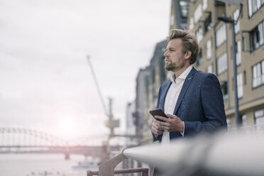 Businessman with cell phone at the riverside - JOSF02050