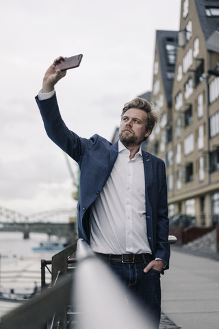 Geschäftsmann macht ein Handy-Selfie am Flussufer, lizenzfreies Stockfoto