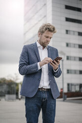 Businessman using cell phone in the city - JOSF02054