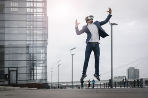 Businessman wearing VR glasses jumping in the city - JOSF02058