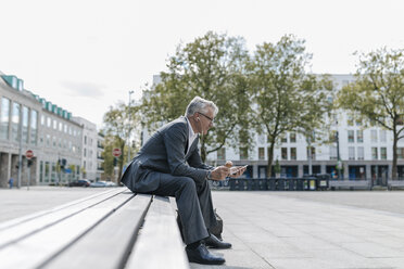 senior businessman sitting on stairs, talking on the phone, eating ice cream - GUSF00259