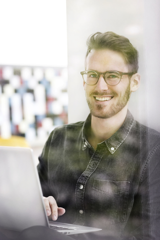 Portrait of smiling man using laptop stock photo