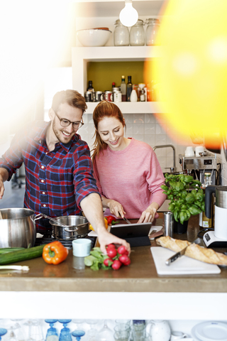 Glückliches junges Paar mit Tablet kochen zusammen in der Küche, lizenzfreies Stockfoto