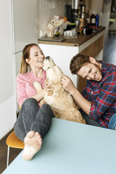 Glückliches junges Paar spielt mit Hund zu Hause - PESF00782