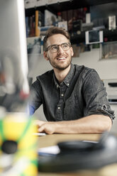 Porträt eines lächelnden Mannes, der zu Hause am Schreibtisch arbeitet - PESF00787