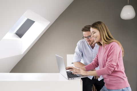 Smiling man and woman sharing laptop stock photo