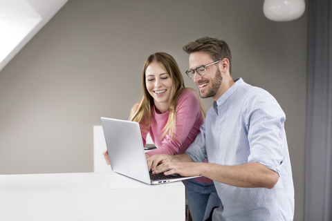 Glücklicher Mann und glückliche Frau teilen sich einen Laptop, lizenzfreies Stockfoto