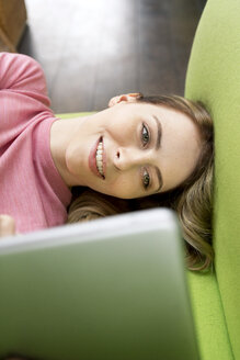 Porträt einer lächelnden Frau, die auf der Couch liegt und ein Tablet benutzt - PESF00800