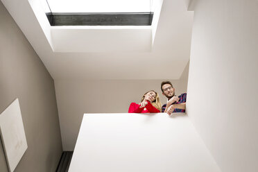 Portrait of smiling young couple on upper floor under roof window - PESF00815