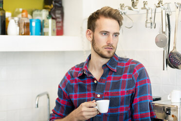 Nachdenklicher junger Mann mit einer Tasse Espresso in der Küche zu Hause - PESF00819