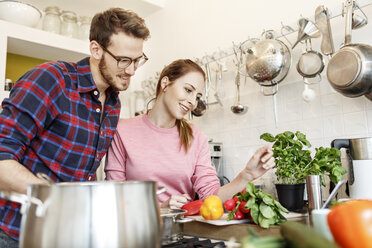 Happy young couple cooking together in kitchen - PESF00848