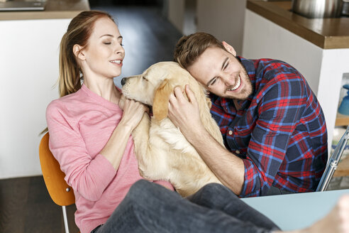 Glückliches junges Paar, das mit seinem Hund zu Hause kuschelt - PESF00861