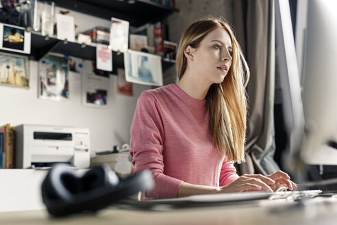 Junge Frau arbeitet am Computer am Schreibtisch zu Hause - PESF00877