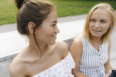 Zwei lächelnde junge Frauen unterhalten sich im Freien - KNSF03052