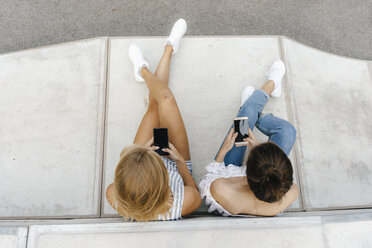 Zwei junge Frauen benutzen Handys in einem Skatepark - KNSF03054