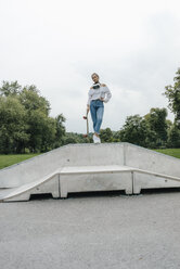 Junge Frau mit VR-Brille in einem Skatepark mit Skateboard - KNSF03057